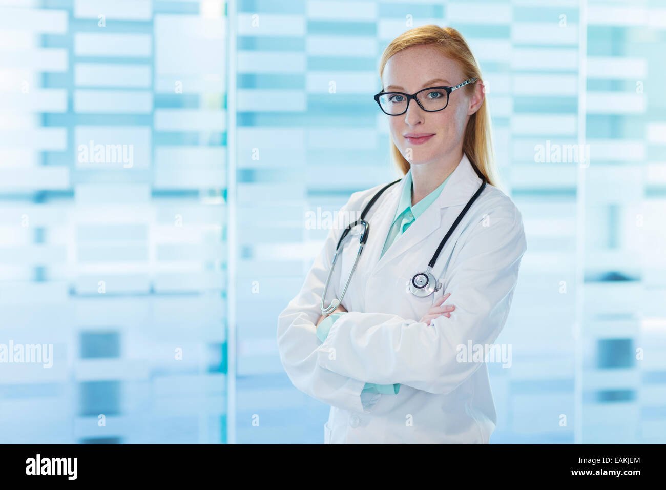 Porträt von lächelnden Ärztin Brillen-und Laborkittel stehend mit Arme gekreuzt Stockfoto