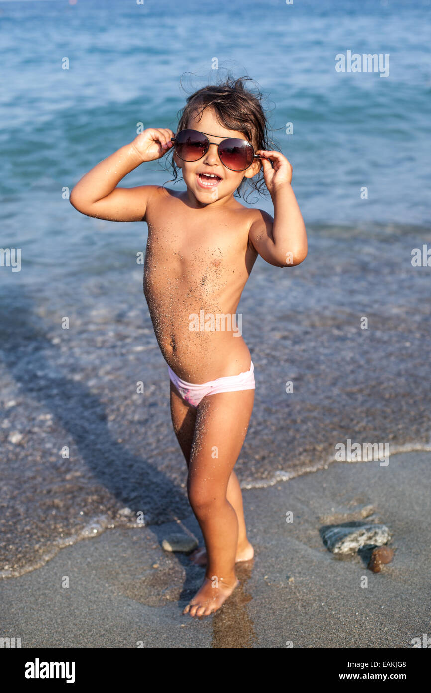 Lustige Babymädchen mit großen Sonnenbrille am Meer. Stockfoto