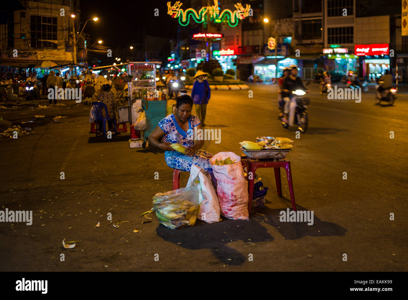 Frau Verkäufer Verkauf von gegrilltem Mais auf dem Nachtmarkt in den Straßen von Tra Vinh, Vietnam. Stockfoto