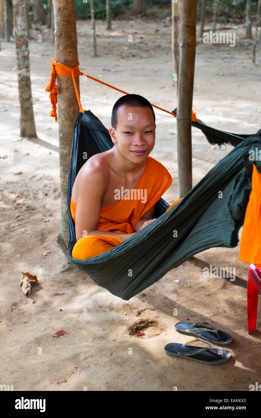 Junger vietnamesischer Mönch im Khmer-Theravada-buddhistischen Kloster in Tra Vinh entspannt in einer Hängematte mit seinem Handy. Stockfoto