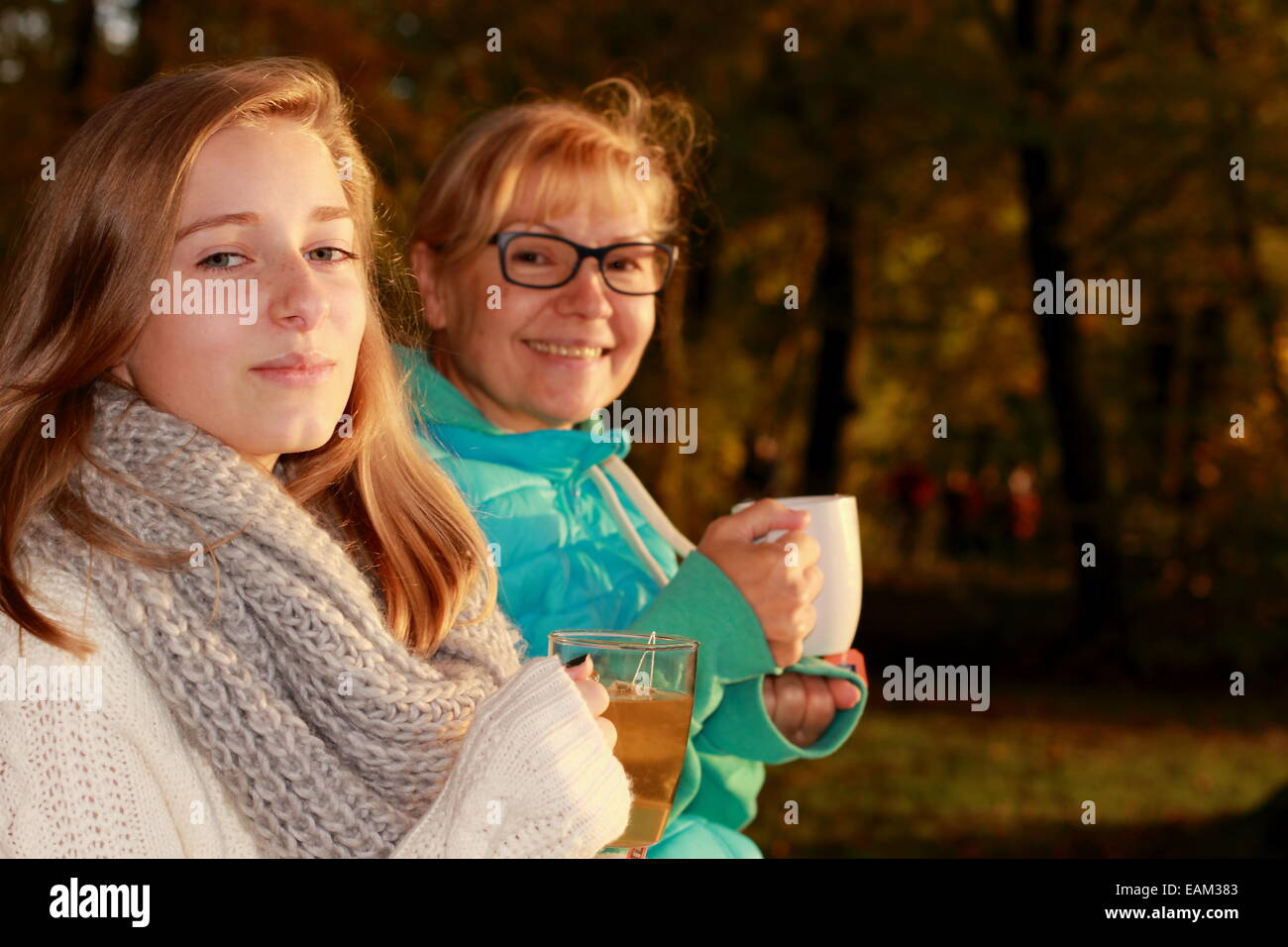 Tochter und Mutter trinken Tee im Herbst Park, horizontale Stockfoto