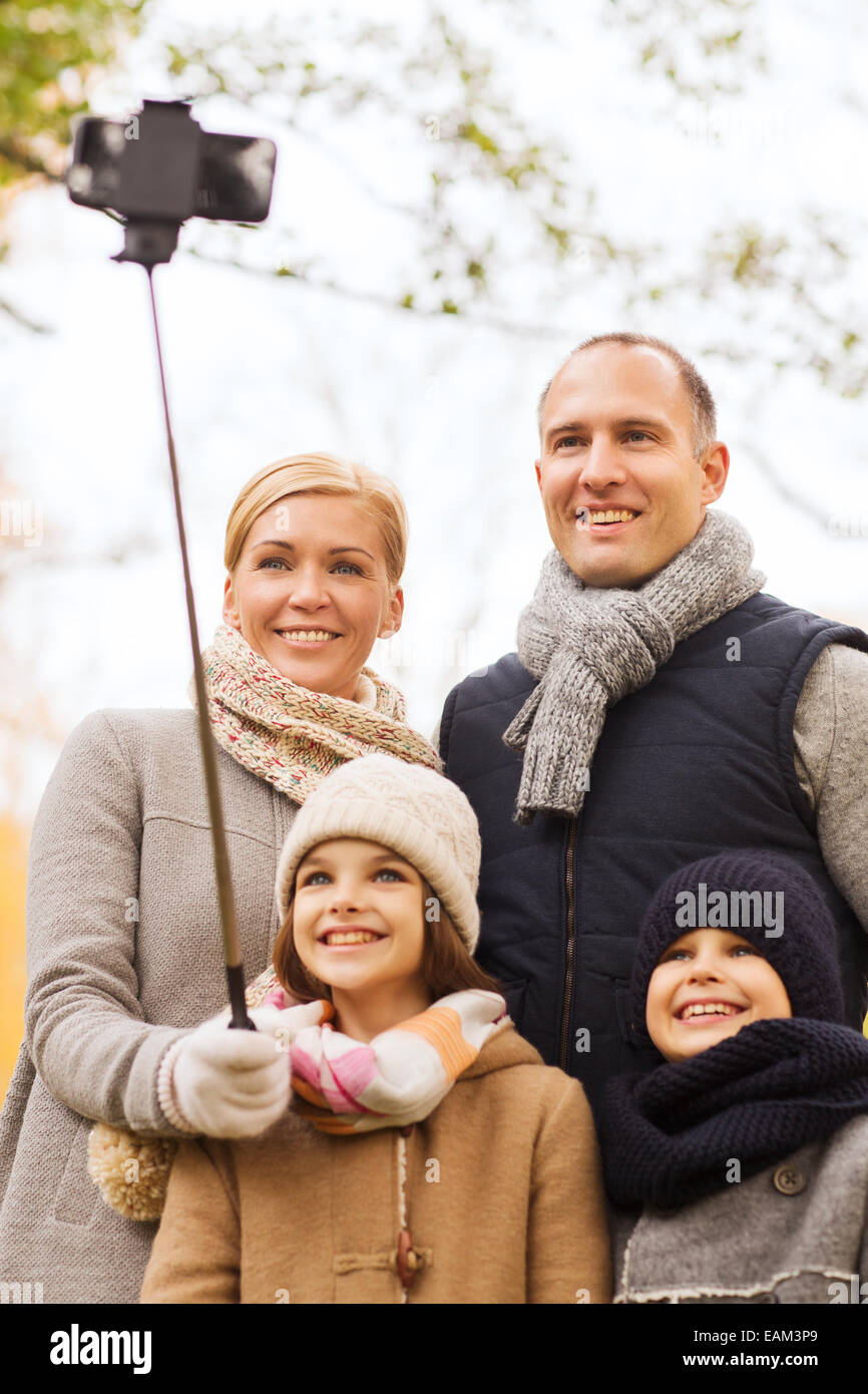 glückliche Familie mit Smartphone und Einbeinstativ in park Stockfoto