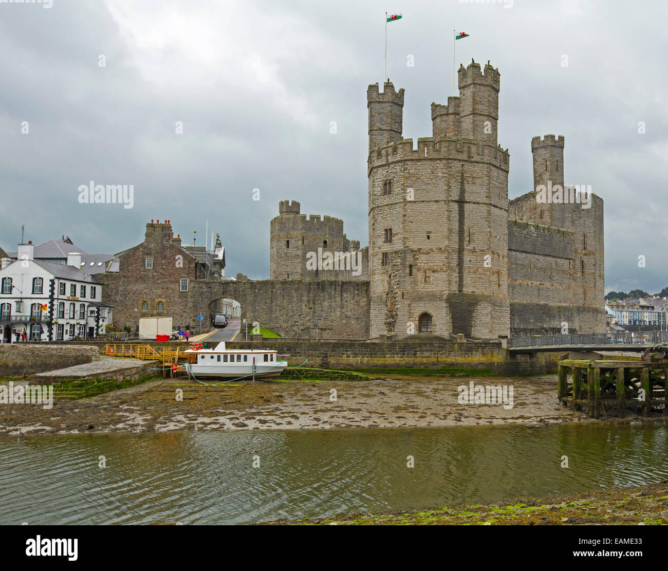 Riesige & spektakuläre 13. Jahrhundert Caernarfon Castle Verzwergung angrenzenden Stadt Pub, überragt River Seiont unter Gewitterhimmel, Wales Stockfoto