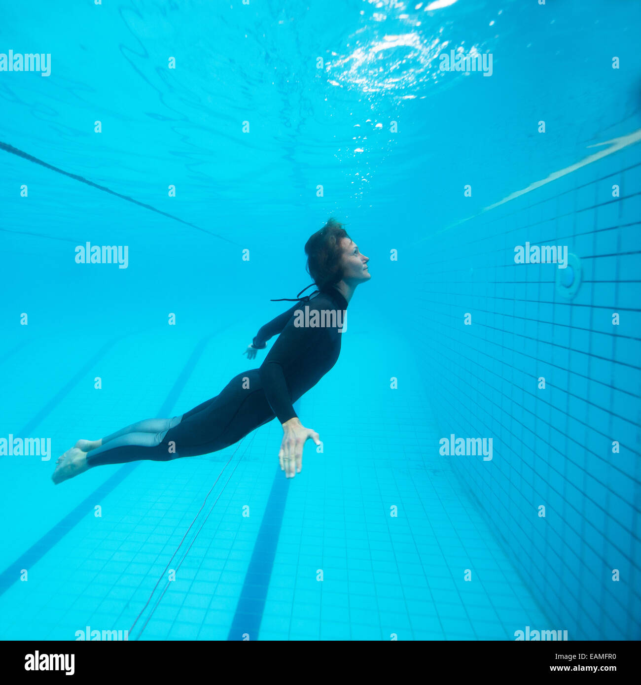 Weibliche Taucher unter Wasser im Schwimmbad mit Augen zu öffnen, auf der Suche nach oben in Richtung Oberfläche Stockfoto