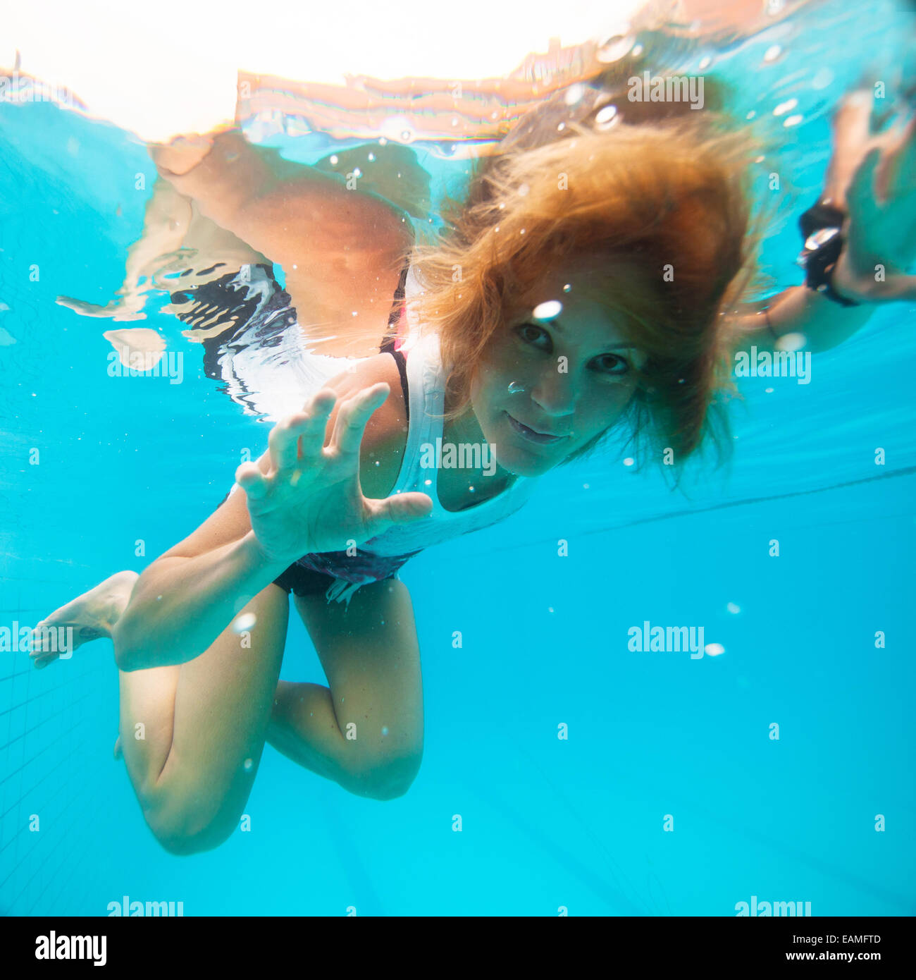 Hübsche Frau mit Augen offen auf der Suche und lächelnde Weile unter Wasser im Schwimmbad Stockfoto