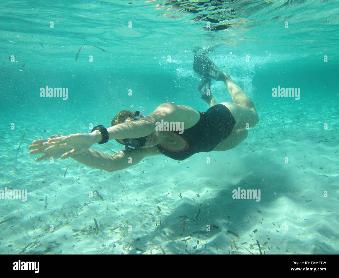 Weibliche Schwimmer tragen, Maske und Flossen Tauchen Unterwasser im Ozean über sandigen Boden Stockfoto