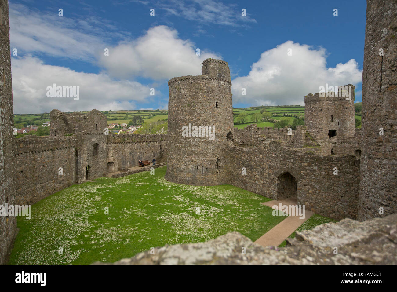 Blick vom hohen Steinmauer von beeindruckenden Innenteil & Türme des 13. Jahrhunderts Kidwelly Burgruine unter blauem Himmel in Wales Stockfoto