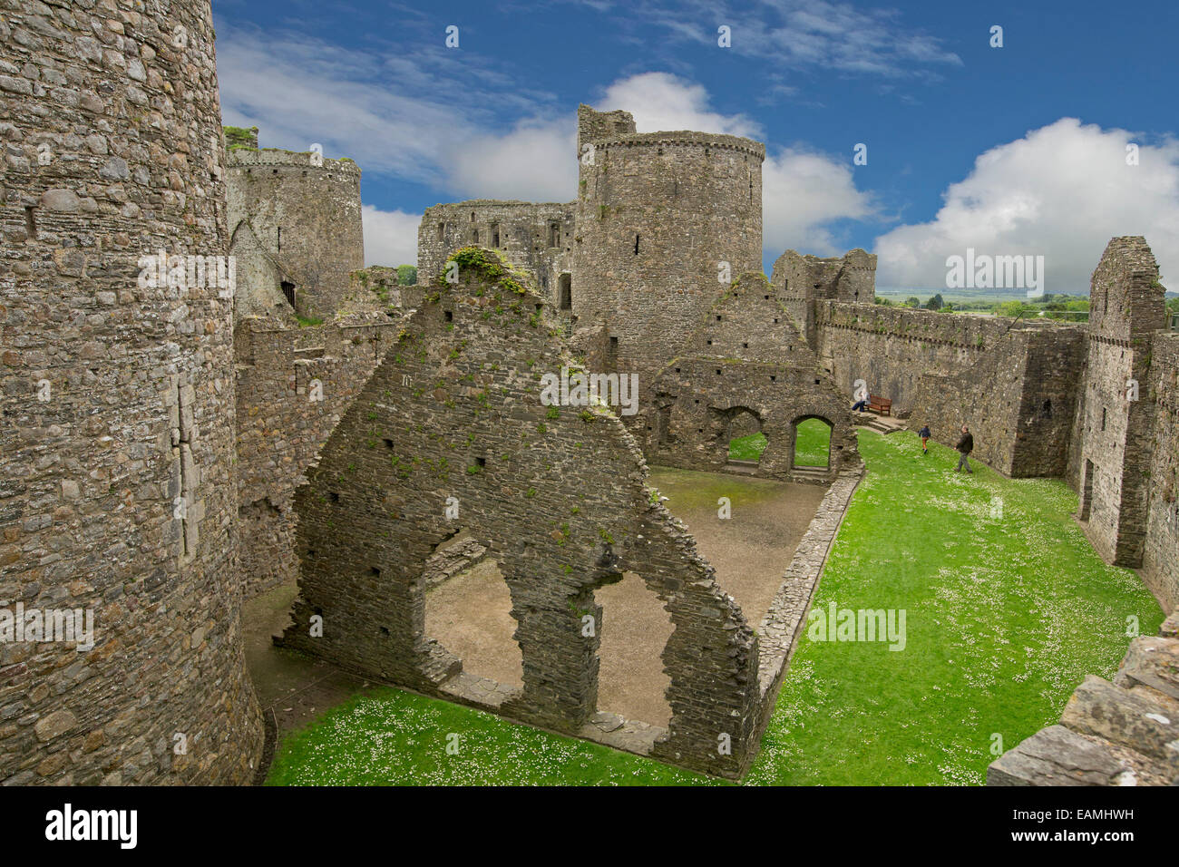 Blick vom hohen Steinmauer von beeindruckenden Innenteil & Türme des 13. Jahrhunderts Kidwelly Burgruine unter blauem Himmel in Wales Stockfoto