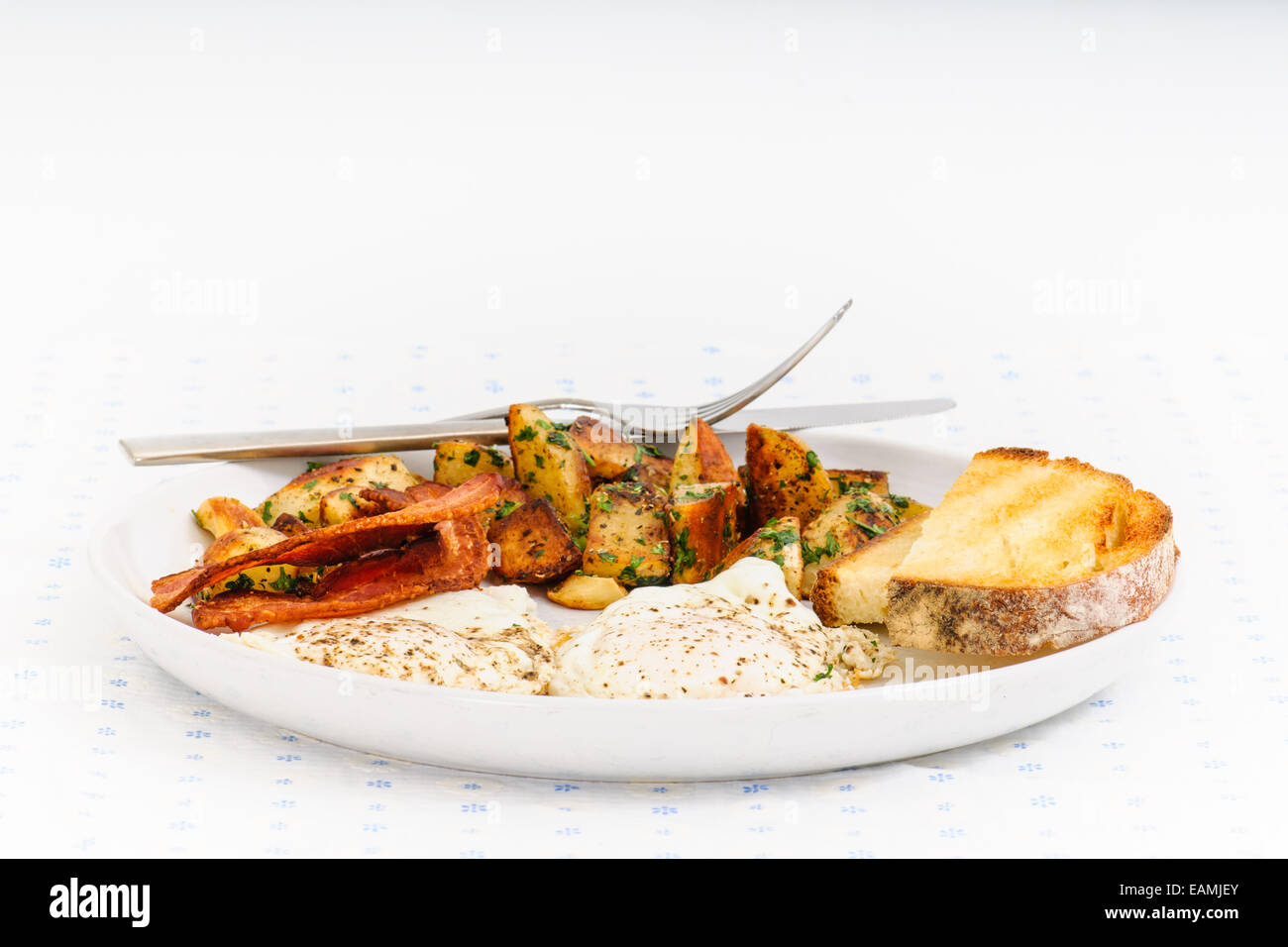 Nachsichtig Frühstück mit Speck, Kartoffel-Rösti, Sonnenseite Eiern und Sauerteig Toast. Stockfoto