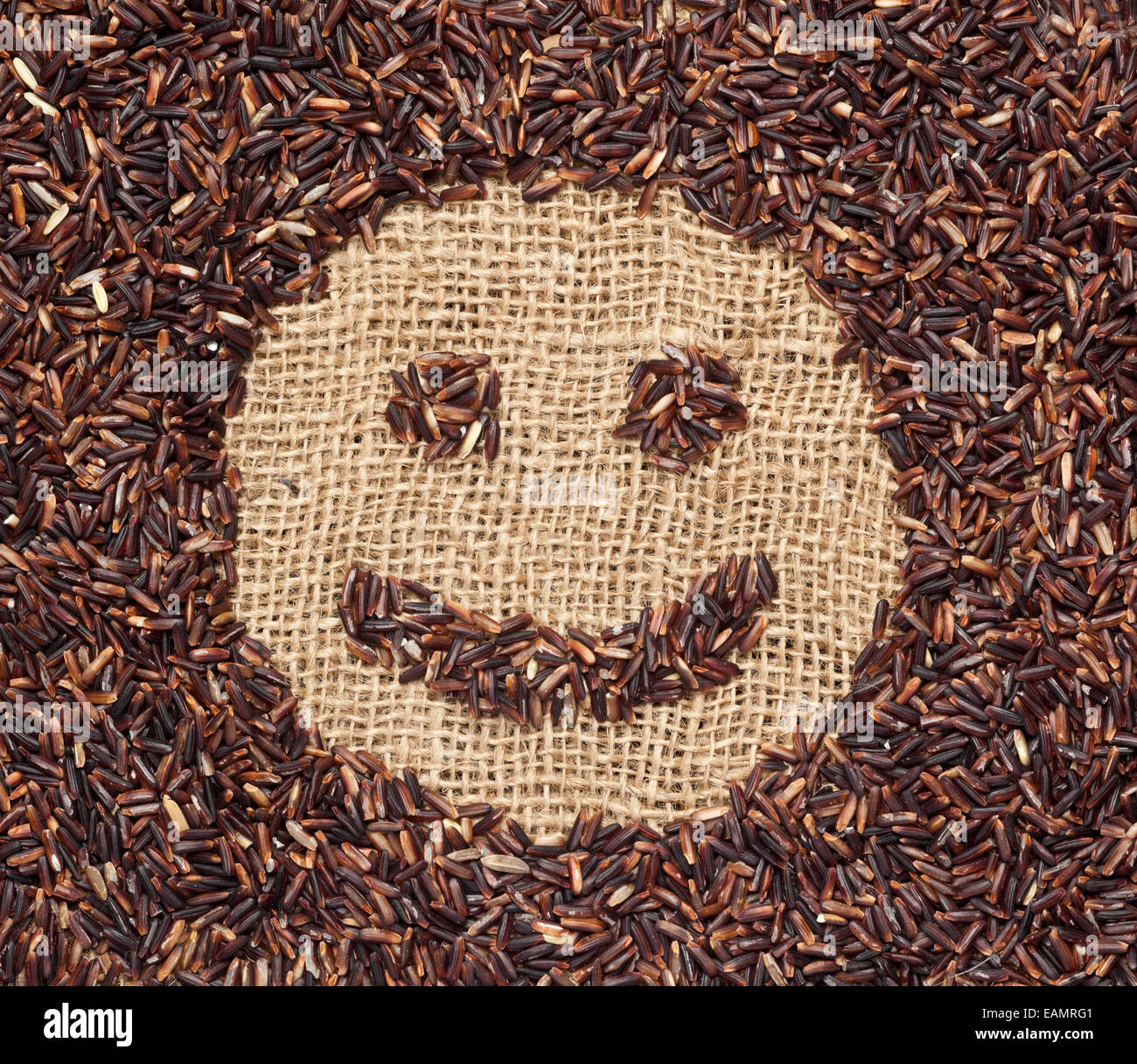 Roter Reis bilden ein Smiley-Gesicht auf Jute-Stoff Stockfoto