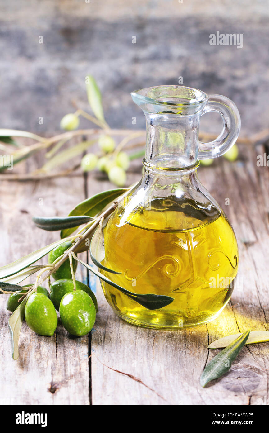Krug von Olivenöl mit Ölzweig über Holztisch. Stockfoto