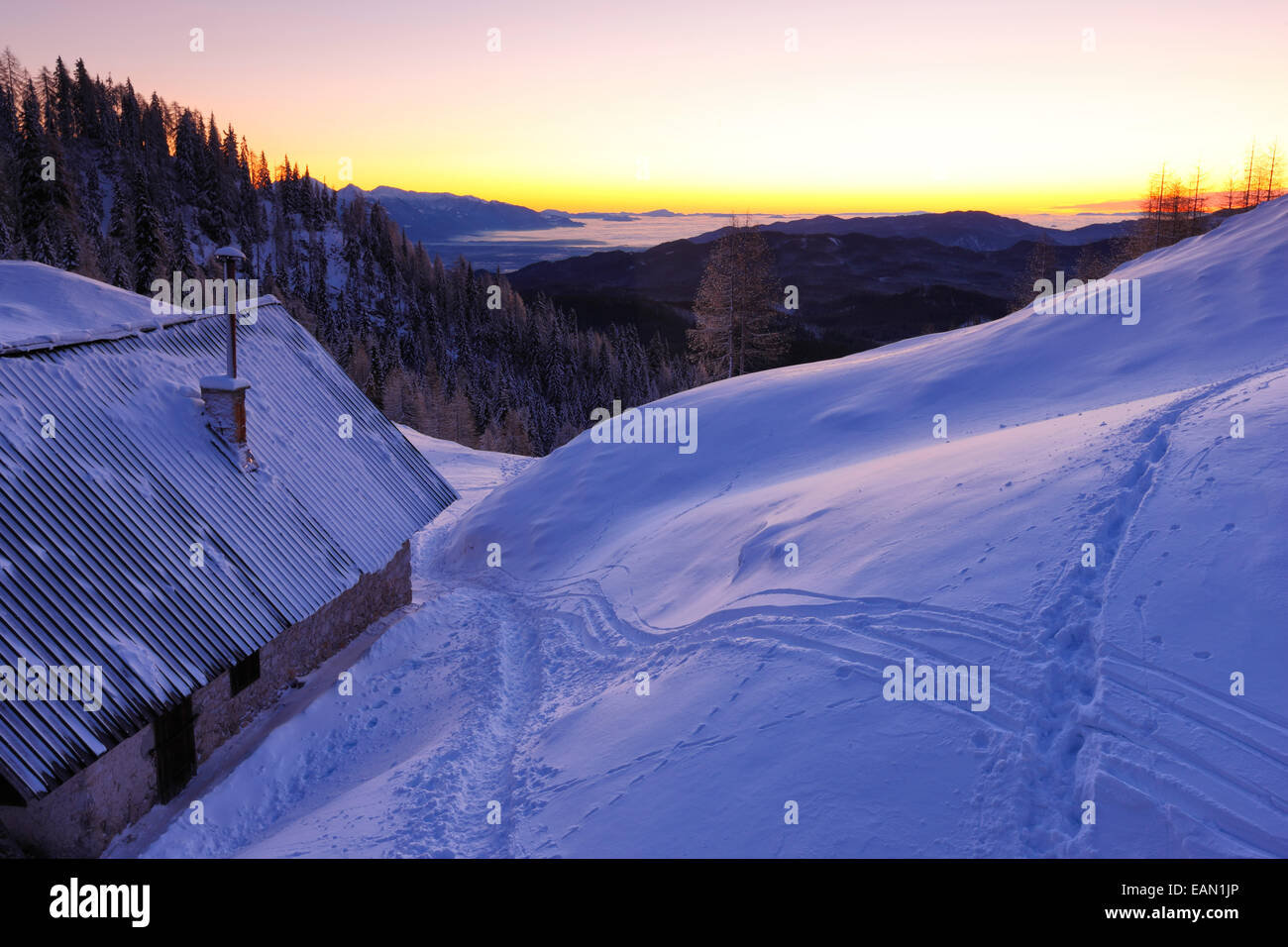 Berghütte bei Sonnenaufgang im Winter. Sonnenaufgang in den slowenischen Alpen. Stockfoto
