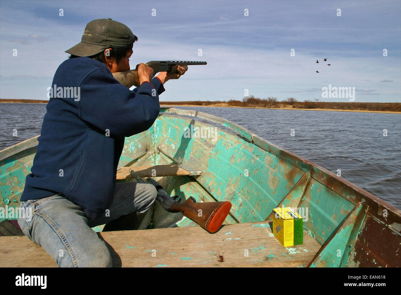 Alaska Native Yu'pik Mann Jagd auf Vögel mit einem Gewehr von einem kleinen Boot in der Nähe von Kwethluk, Alaska. Stockfoto