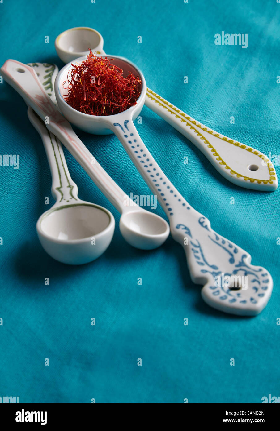 Safran auf einem dekorativen Messlöffel auf Türkis Hintergrund Stockfoto
