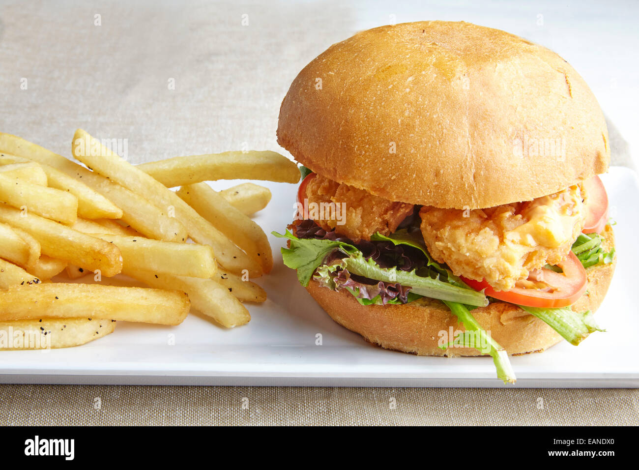 Garnelen-Po-Boy mit Pommes Frites auf einem weißen Teller mit roten Streifen Tischdecke Stockfoto