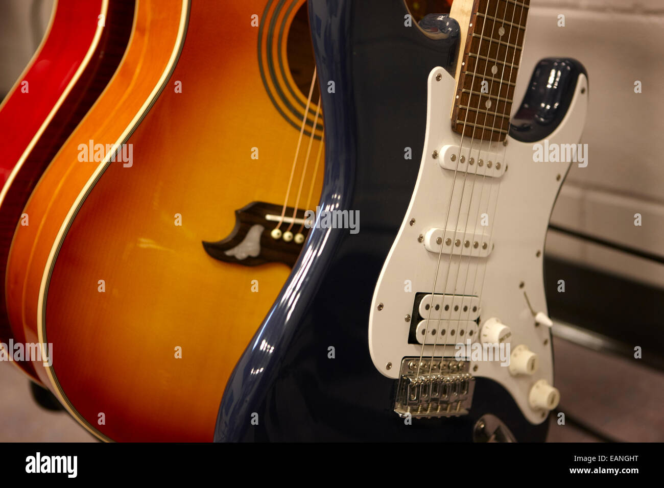 elektrische und akustische Gitarren auf einem Gestell in einem Musik-Übungsraum Stockfoto