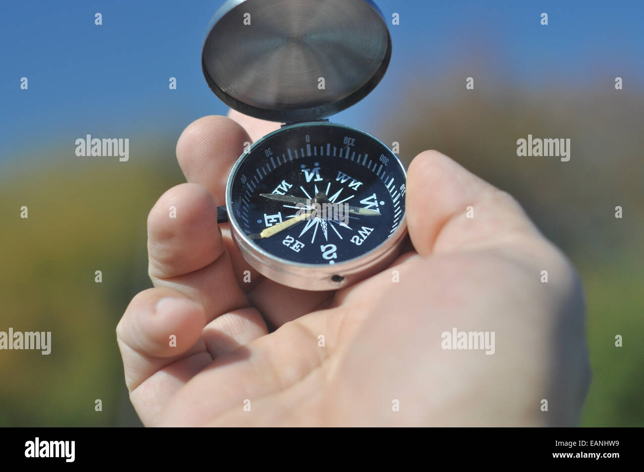Kompass in der hand. Der Magnetkompass liegt in die Hand eines Mannes auf einem Hintergrund von Natur. Stockfoto