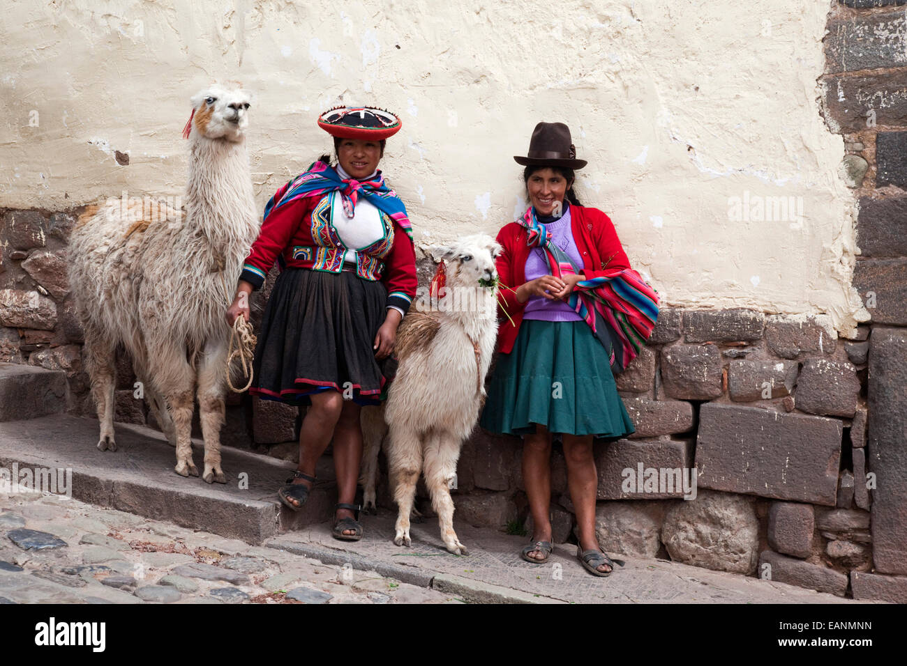 Zwei Frauen in Tracht posiert mit Alpakas für Touristen in Cusco, Cuzco, Peru, Südamerika Stockfoto