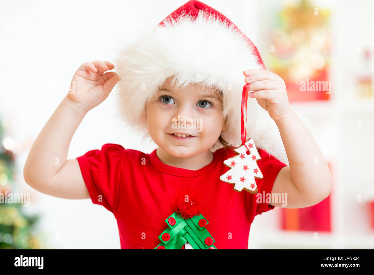 Kind Mädchen in Nikolausmütze halten Weihnachtsplätzchen Stockfoto