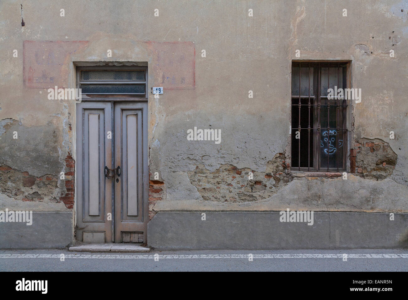 Verblichene Stuck Putz Schaufenster Fassade entlang der Straße in Novello Stockfoto