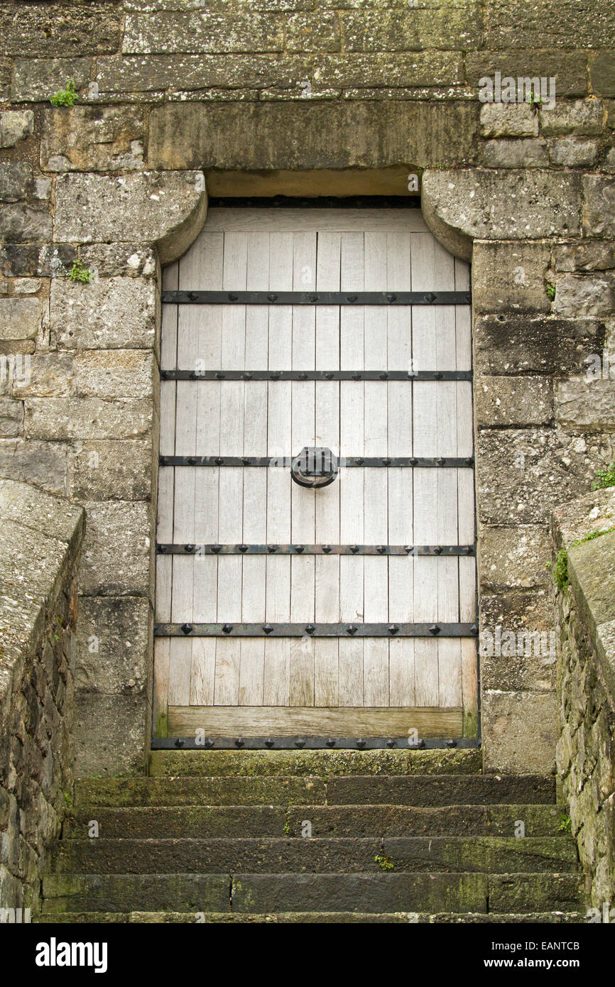 Große weiße gemalte hölzerne Tür an Spitze der alten Steintreppen & in dicken Steinmauern von Caernarfon Castle, Wales Stockfoto