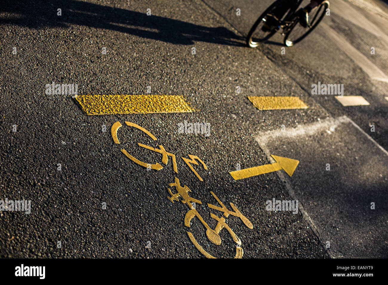 Biker/Radfahrer an einer Kreuzung in einer Stadt, wirft einen langen Schatten Stockfoto