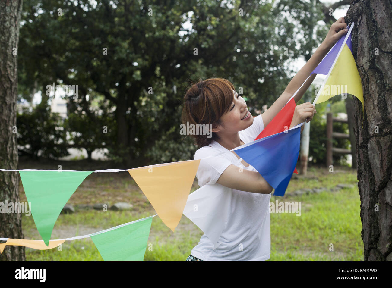 Eine Frau in einem Kyoto-Park eine bunte Reihe von Fahnen hochhalten. Stockfoto