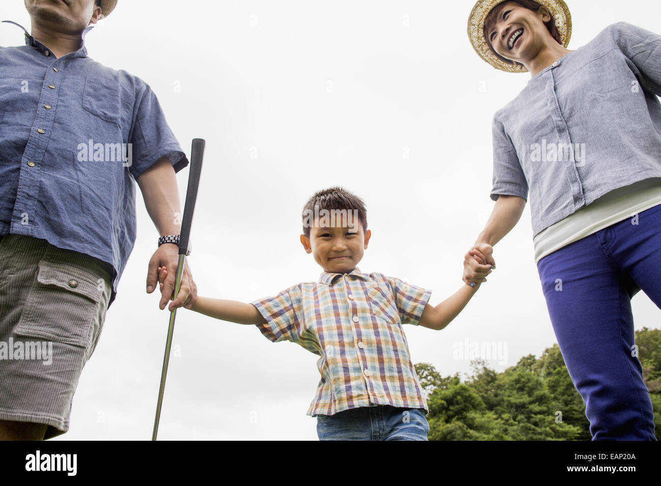 Familie auf einem Golfplatz. Zwei Eltern und ein Junge Hand in Hand. Stockfoto