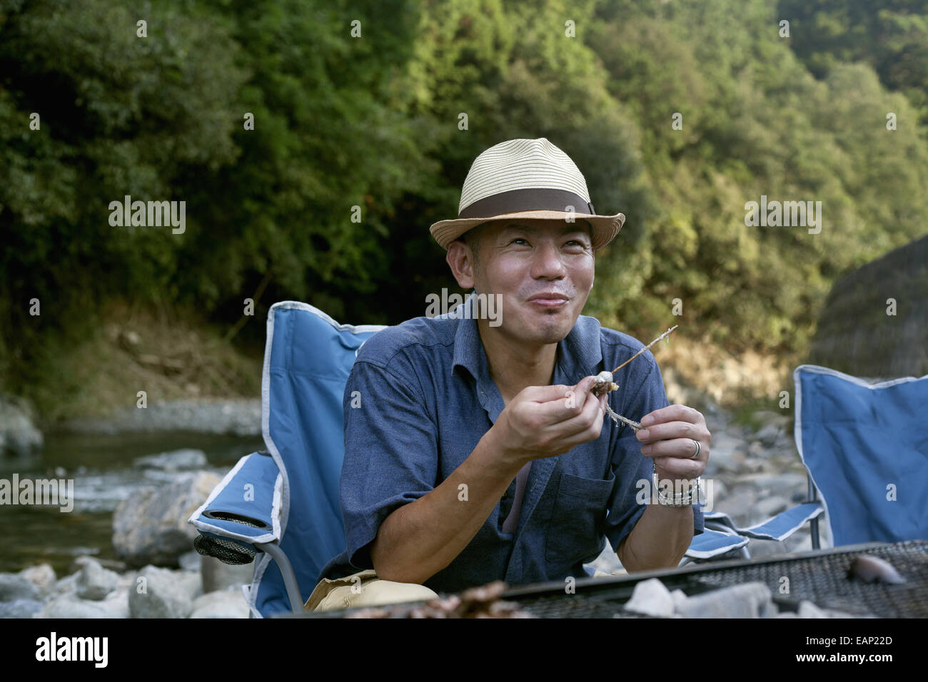 Mann isst ein gegrillter Fisch bei einem Picknick. Stockfoto