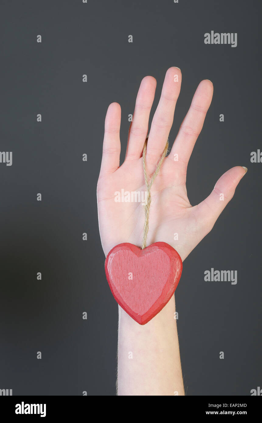 Zarte Frauenhand hält eine hölzerne Liebe Herz Stockfoto