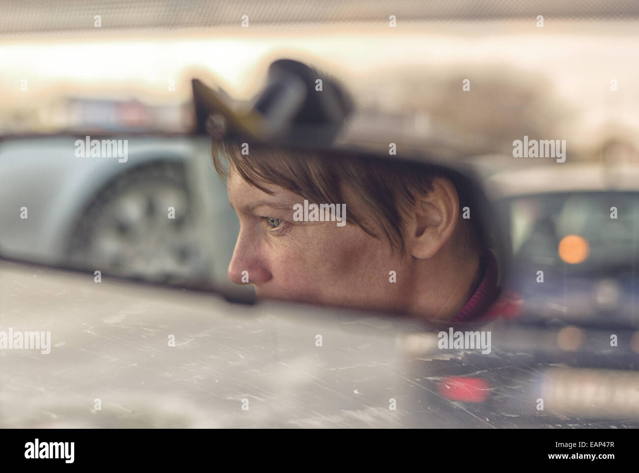 Weibliches Gesicht im Rückspiegel des Autos während der Fahrt durch die Stadt Verkehr Rush hour Stockfoto