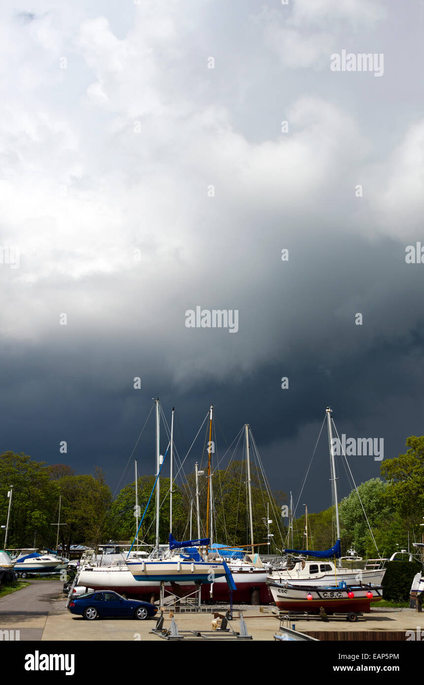 Yachten an Land in der Werft. Herbst-Szene mit bedrohlichen Gewitterwolken und Porsche Fahrzeuge Stockfoto