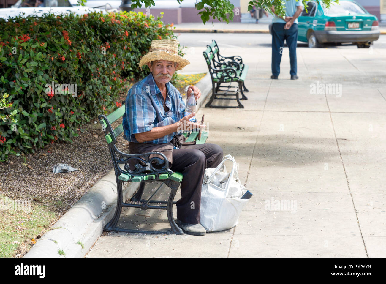 CIENFUEGOS, Kuba - 7. Mai 2014: Alter Mann mit Stroh Sobrero sitzen auf einer Bank im Quadrat von Cienfuegos, Kuba Stockfoto