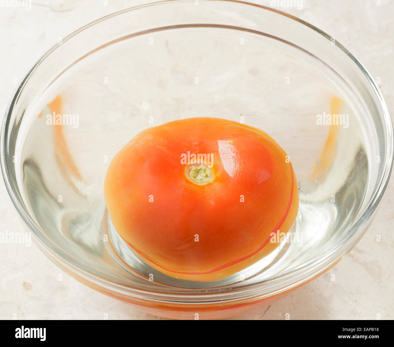 Tomaten in Schüssel mit Wasser mit Haut aufteilen Stockfoto