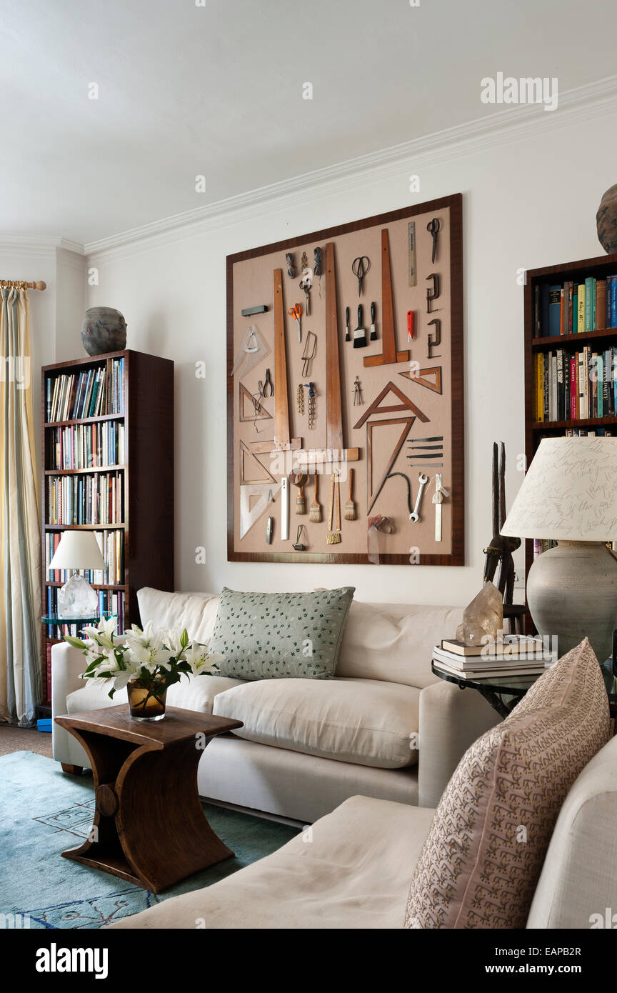Eine Anzeige verschiedener Werkzeuge - Pinsel, hölzerne Dreiecke und Bild-Ketten - auf eine Wohnzimmerwand Kastenrahmen Stockfoto