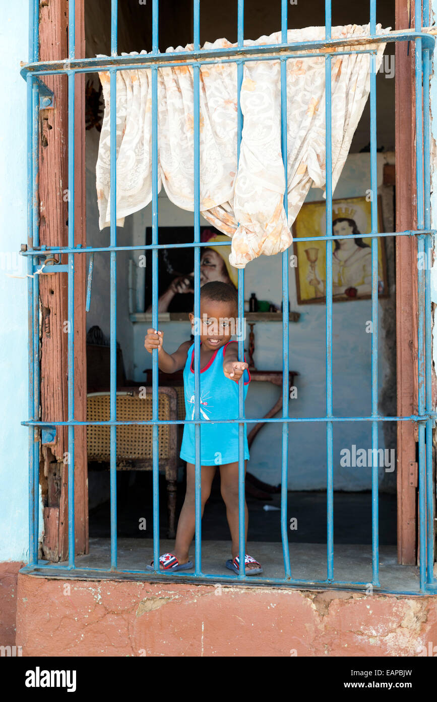TRINIDAD, Kuba - 8. Mai 2014: Kleiner Junge schaut aus dem Fenster seines Hauses Stockfoto