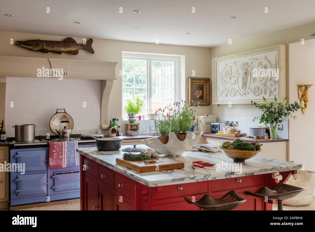 Landhausküche mit Marmor gekrönt Metzger Insel, lila Rayburn und großen klassischen Basrelief Stockfoto