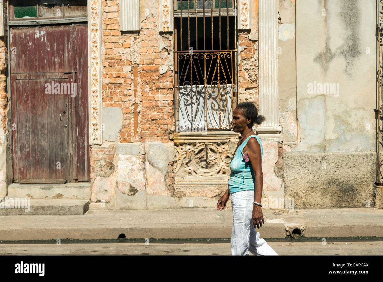 MATANZAS, Kuba - 10. Mai 2014: Gemischte Seniorin geht durch eine beschädigte Innenstadt Straße in der Stadt Matanzas, Kuba Stockfoto