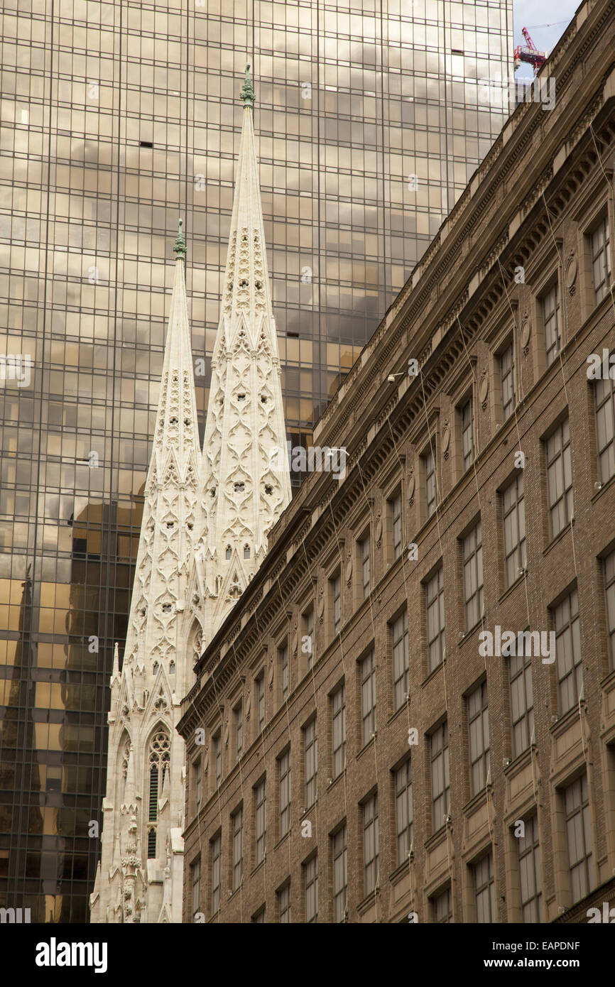 Die Trwin Türme der St. Patricks Kathedrale zeichnen sich inmitten der eklektischen Architektur entlang der 5th Avenue in New York City. Stockfoto