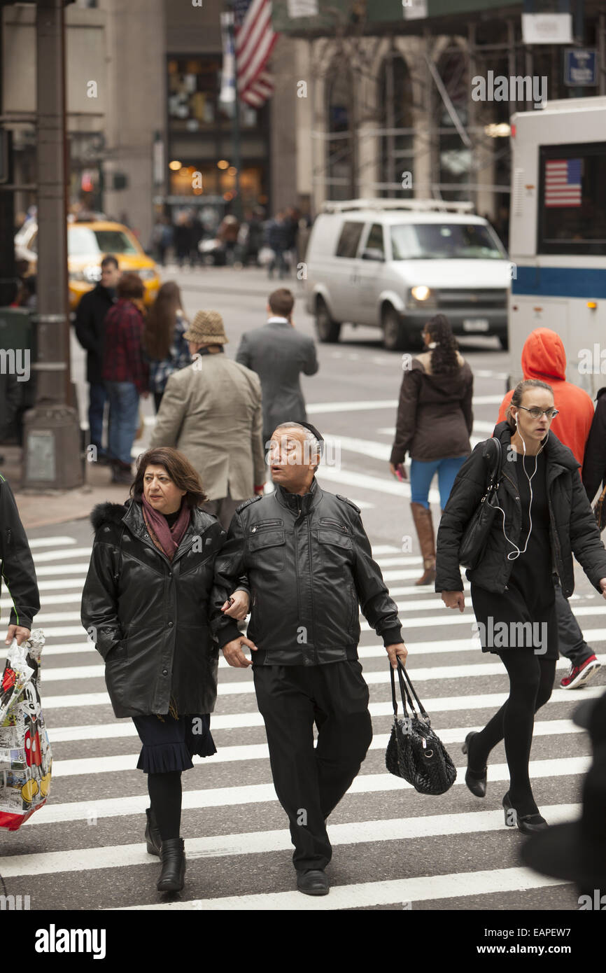 5th Avenue an der 42nd Street gehört zu den am meisten ständig überfüllten Ecken in New York City. Mann trägt seine Frau Handtasche. Stockfoto