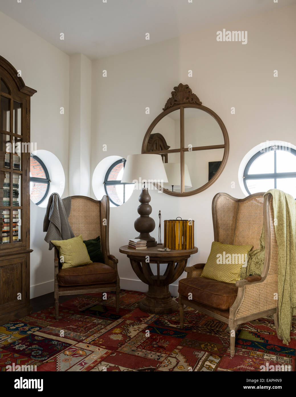 Paar geflügelte zurück Stühle im Zimmer mit großen gemusterten Teppich, Antikglas verkleidete Fenster im Schrank und Runde Port Loch Stil. Stockfoto
