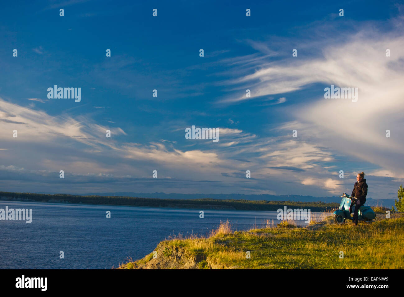 Frau sitzt auf einem Jahrgang 1959 Vespa Motorroller mit Blick auf Knik Arm, Tony Knowles Coastal Trail, Anchorage, Alaska Stockfoto