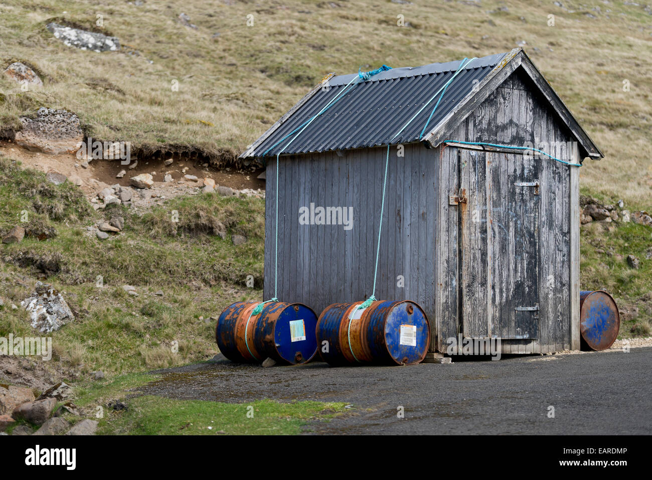 Fässer gefüllt mit Sand, die Hütte auf dem Boden zu halten bei starkem Wind, Kirkja, Fugloy, Norðoyar, Färöer Inseln, Dänemark Stockfoto