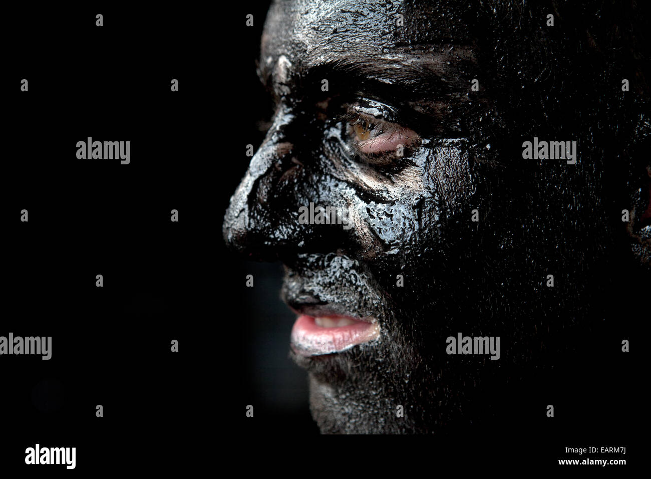 Ein Mensch malt sein Gesicht schwarz als Teil von einem Teufel Kostüm Stockfoto