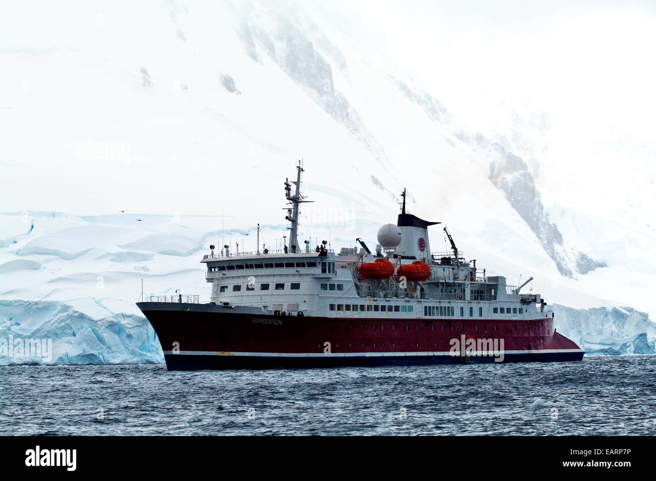 Eine Antarktis Kreuzfahrt Schiff durch eine Schnee- und verkrustete Gipfel verankert. Stockfoto