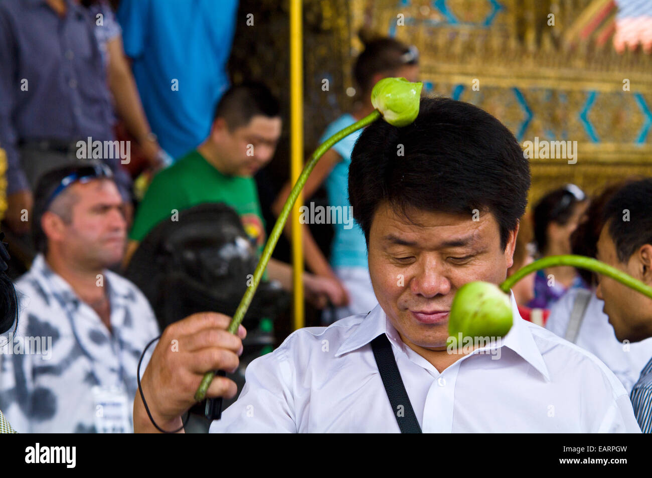 Ein Anbeter spricht ein Gebet und seinen Kopf mit einer Blumenzwiebel berührt. Stockfoto