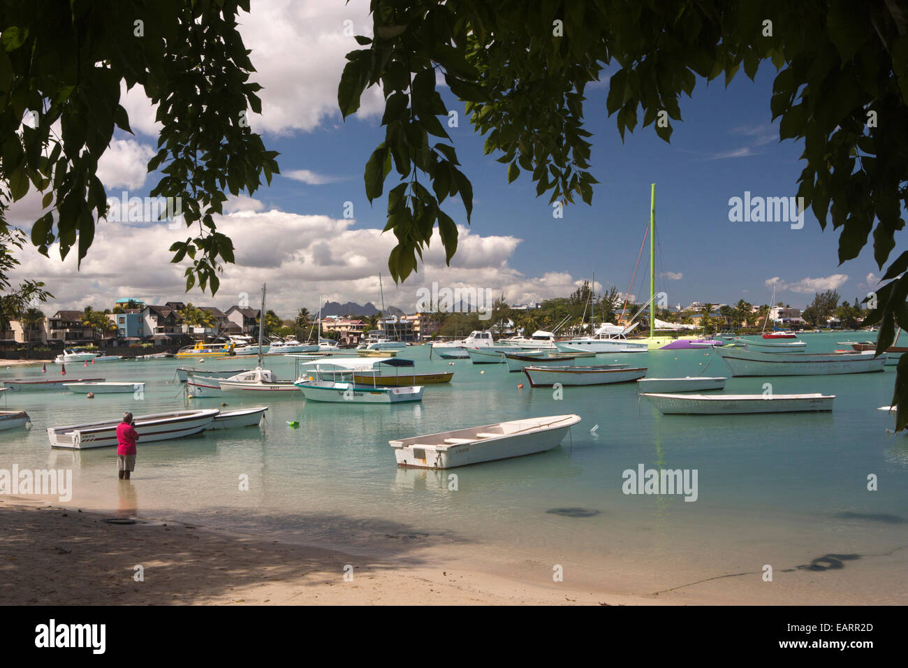 Mauritius, Grand Baie, öffentlicher Strand, Hindu Mann, der betet in Untiefen unter Freizeitboote Stockfoto