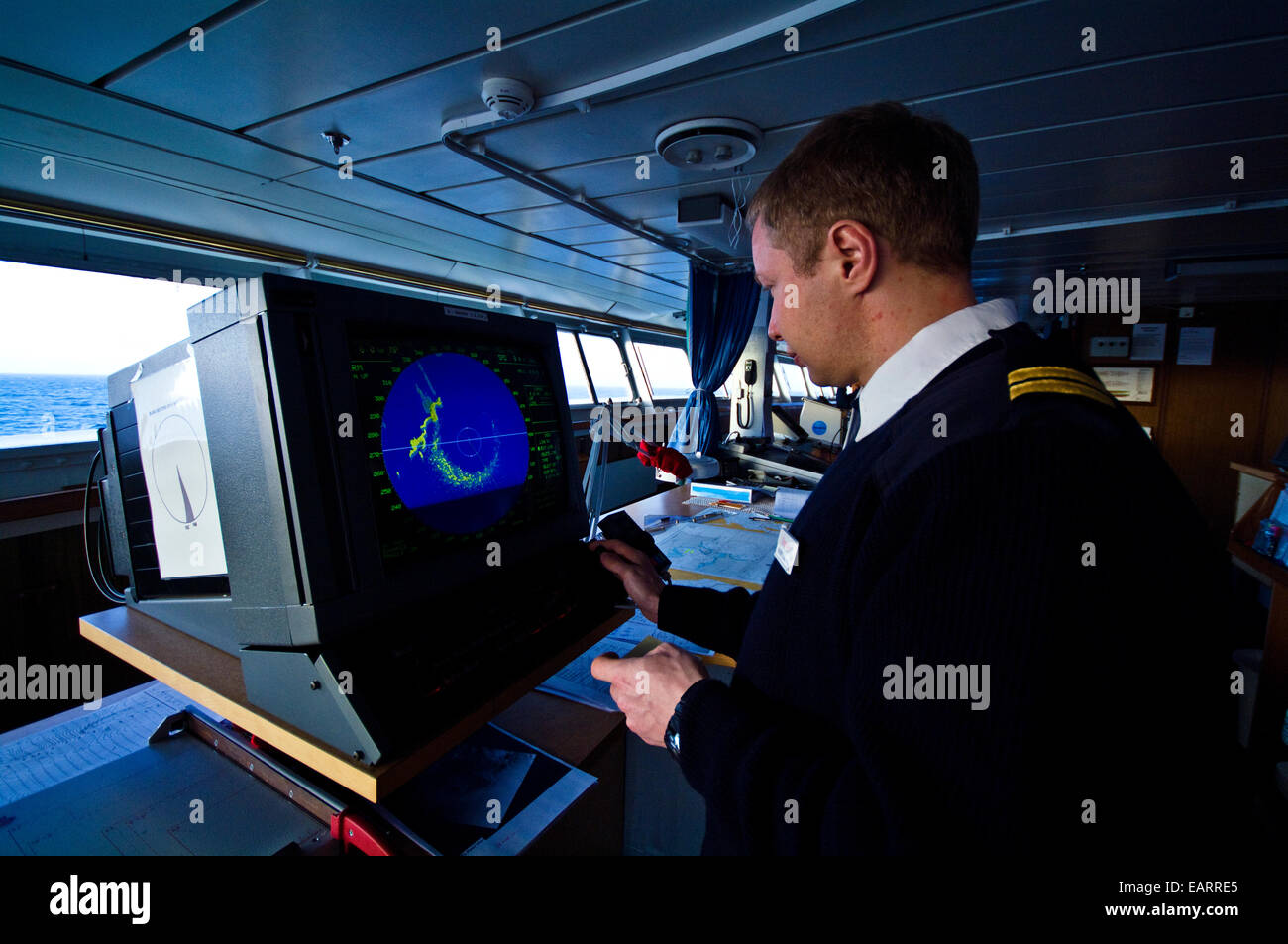 Ein Offizier vom Dienst an Bord eines Schiffes Brücke untersucht einem Radarschirm. Stockfoto