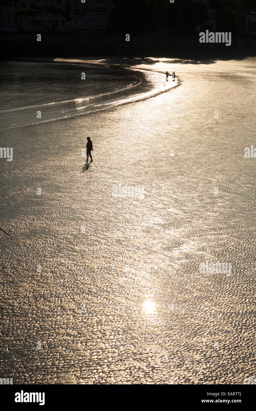 Sonne, Sekt aus nassen Strand bei Ebbe mit Mann zu Fuß zum Rand des Wassers Stockfoto