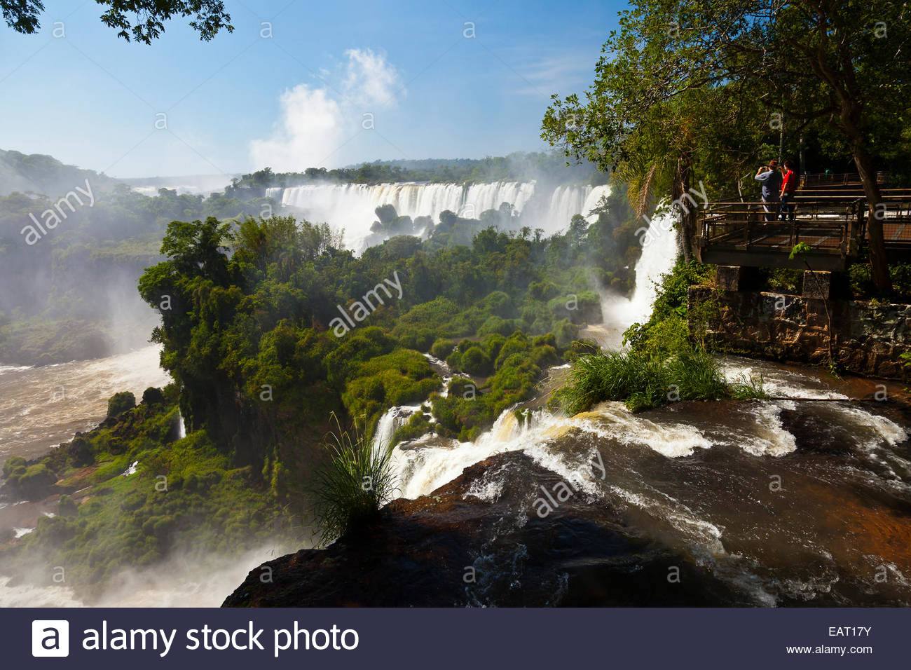 Touristen stehen auf einer Aussichtsplattform mit Blick auf die Iguazu Wasserfälle. Stockfoto